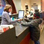 a library clerk helps a child check out a book