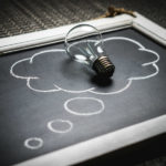 Lightbulb on top of chalkboard with though bubble.