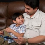 hispanic father and son reading