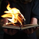 Person holds a book with its pages lit on fire.