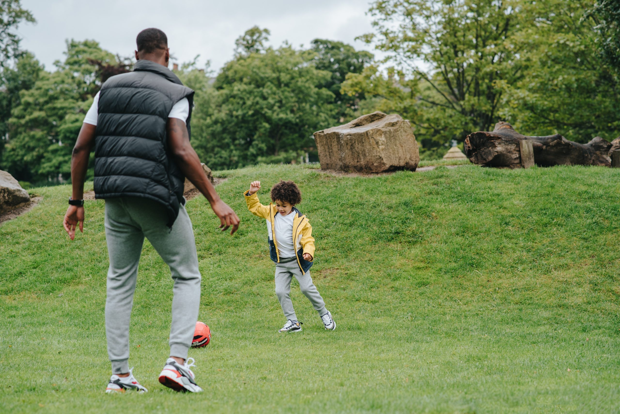 Father and Son play outside with ball.