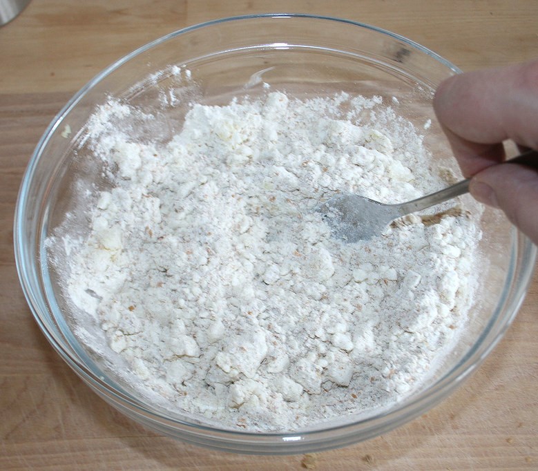 cornstarch in a glass bowl being stirred with a metal spoon