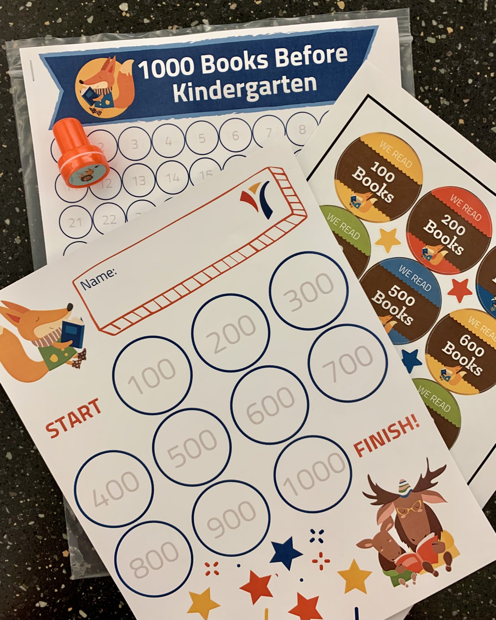 IMG-8391 Photo of array of bookmarks, sticker sheets, and papers with the logo 1000 books before kindergarten all over them