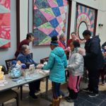 Seniors hand out hot chocolate to library patrons.