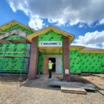 Superior Construction exterior: the brick is up. the exterior insulation is still visible. A banner reading, "welcome" hangs above the main entrance.