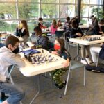 Approximately 15 kids and teens play chess in the triangular bay of YDL-Whittaker.