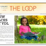 Front page of the Loop. Young girl reading outside and smiling at camera, alongside article titled, "New Faces at YDL."